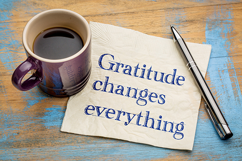 Stock photo of coffee cup and pen with writing about gratitude.