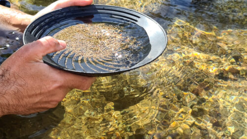 Close-up of a man's hands holding a gold panning prospecting pan Close-up of a man's hands holding a gold panning prospecting pan
