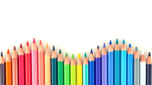 Closeup of coloured pencils lined up in a row on white background copy space
