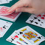 Person picking up a card from a deck of cards with additional cards on the table