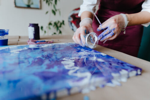 Artist mixing acryl paints on the picture working in fluid art technique Female artist mixing acryl paints on the picture working in fluid art technique. Selective focus.