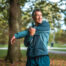 An Asian man in his mid-adult years practices outdoor fitness by stretching in a public park.