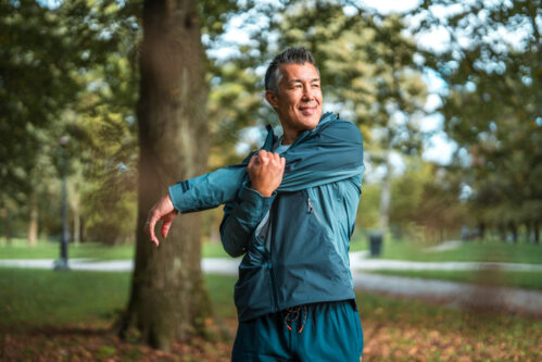 Asian Male Stretching at Park An Asian man in his mid-adult years practices outdoor fitness by stretching in a public park.