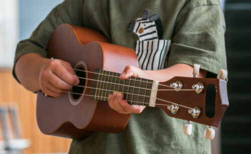 Child playing ukulele, close-up Musical instrument ukulele played by a man