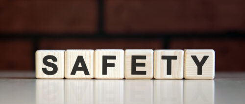 SAFETY - business financial concept on on a dark brick background. Wooden cubes with text SAFETY - business financial concept on on a dark brick background. Wooden cubes with text