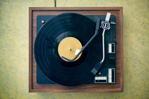 A dusty, dirty, vintage wood and plastic record player from high angle view (directly above)), with retro formica 1960's table. Copy space on table and record; horizontal